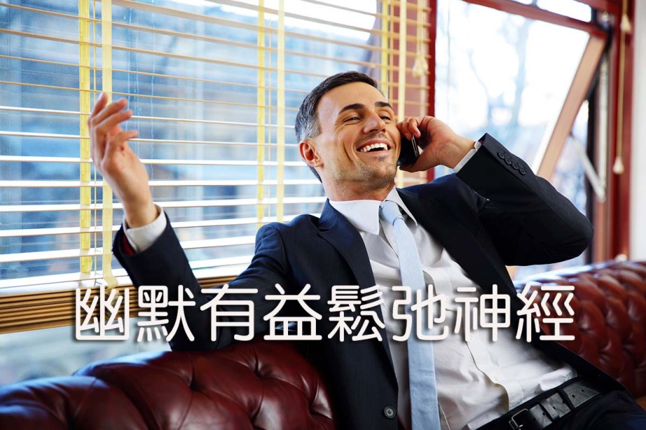 Laughing businessman sitting and talking on the phone at office